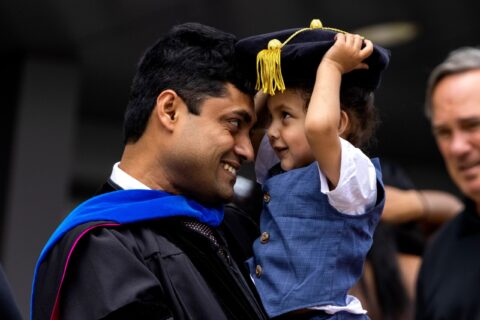 Graduate and child smile at each other