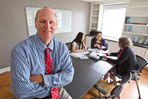 Environmental portrait of John Grable in the Aspire Clinic with a meeting in the background.