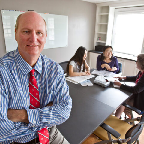 Environmental portrait of John Grable in the Aspire Clinic with a meeting in the background.