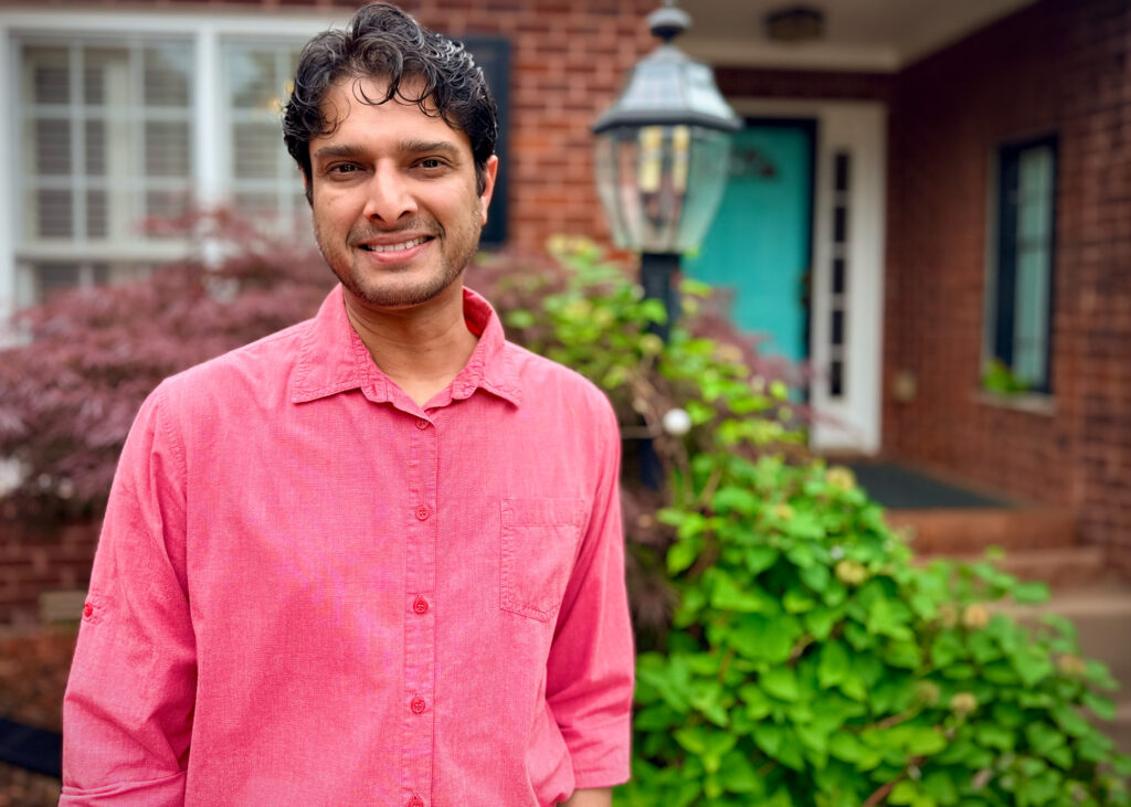 Javad Anjum headshot outside brick house