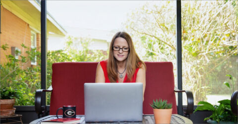 Woman with glasses studies at UGA in front of window