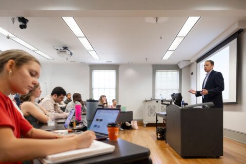 Professor teaches in front of a screen in a college classroom