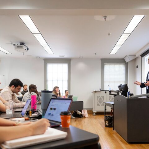 Professor teaches in front of a screen in a college classroom