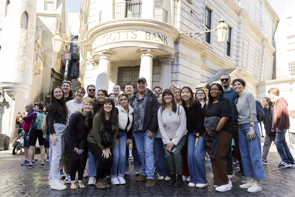 NMI Students and staff pose with UGA alumnus Eric Baker (center) in front of the Gringotts Bank at the Universal Hollywood Studios park.