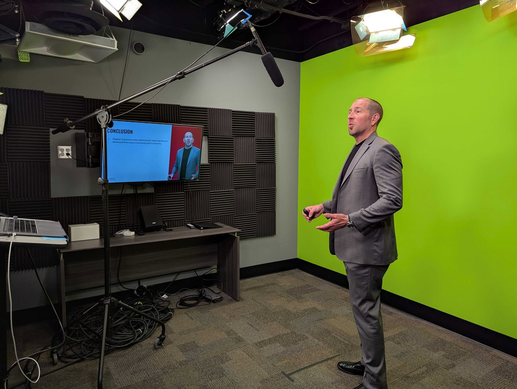 A faculty member records a lecture in front of a green screen