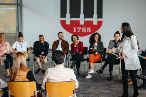 Group of professionals sits in a circle and listens to a trainer