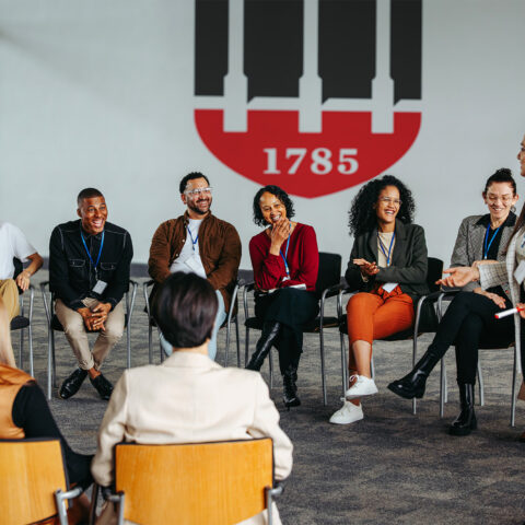 Group of professionals sits in a circle and listens to a trainer